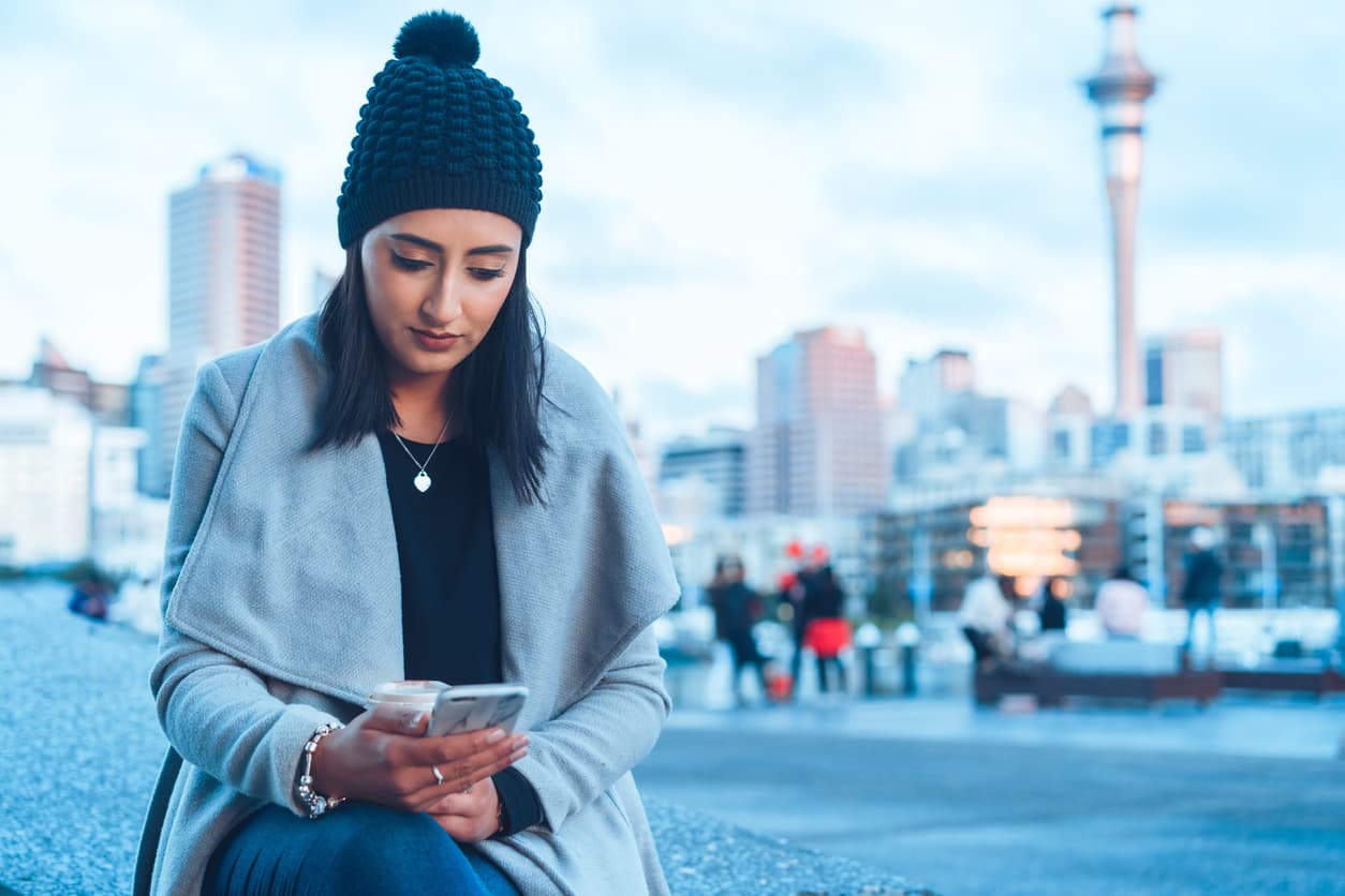 Woman in Auckland checking her bank account on her phone
