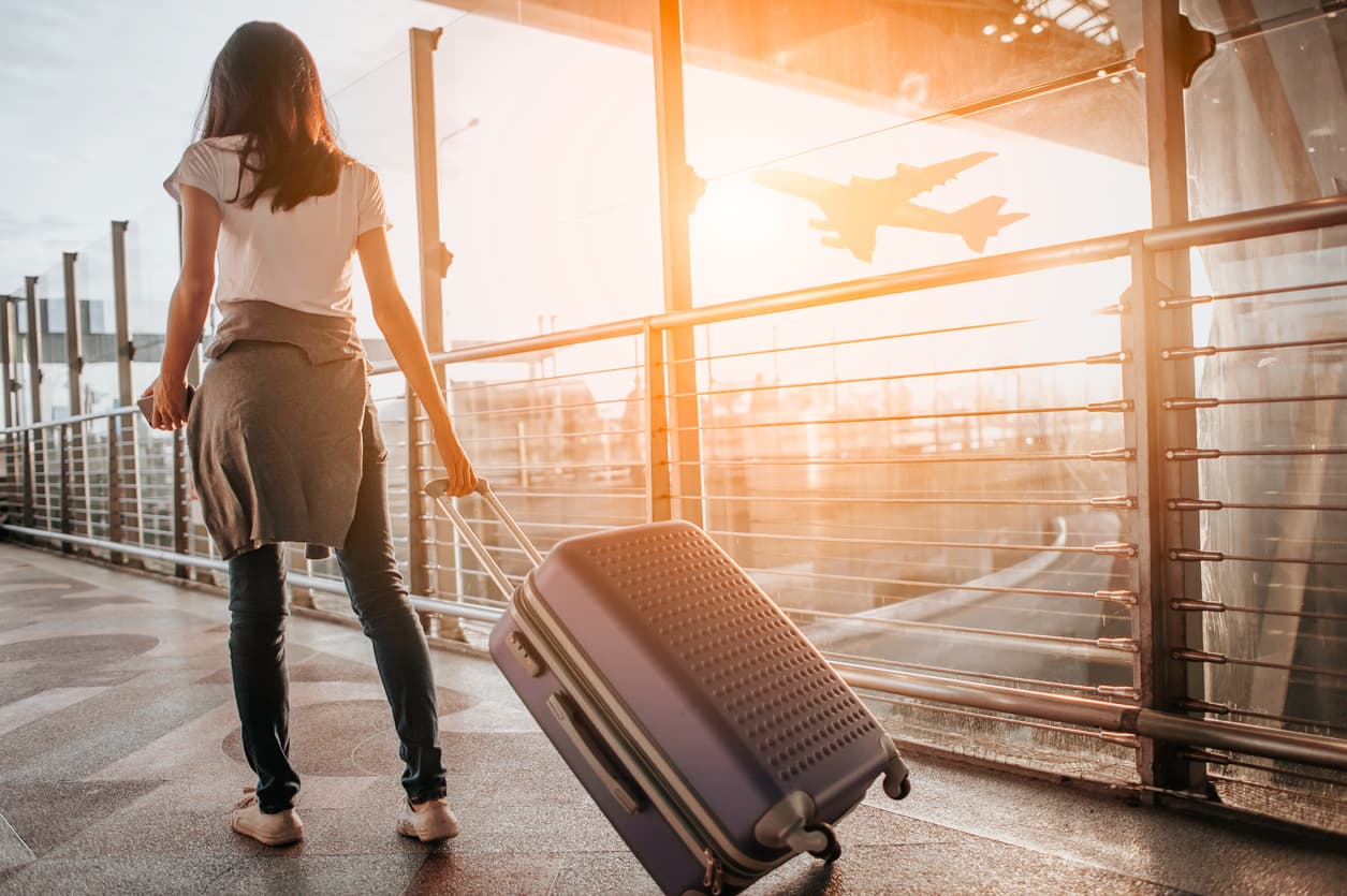 Young woman wheeling a suitcase through the airport