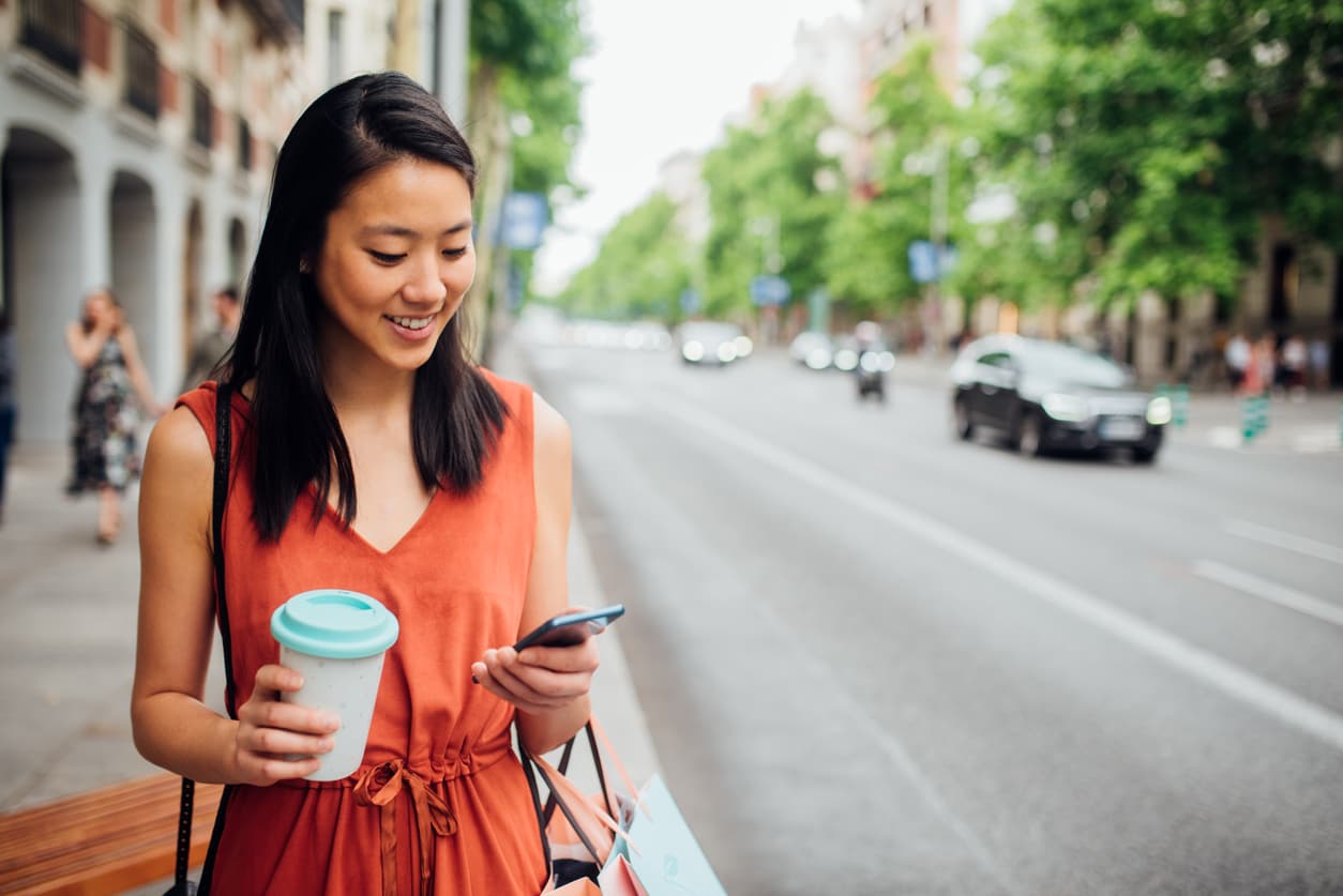 Young woman walking down the street and using her mobile phone